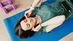 A woman listens to music on her smartphone during yoga.
