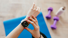 Smartwatch am handgelenk vor Matte und Gewichten.  