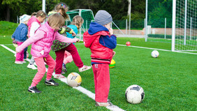 Kinder schießen einen Fußball. 