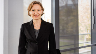 A middle-aged woman is standing in front of a window.