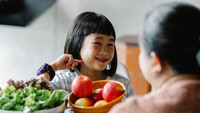 Glückliches asiatisches kleines Mädchen in der Küche