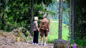 An old couple looks down into a valley.