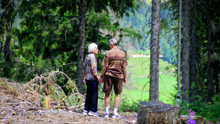 An old couple looks down into a valley.
