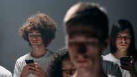 Junge Menschen mit ausdruckslosen Gesichtern blicken auf ihre Smartphones, ein Gesicht im Vordergrund ist verwischt.