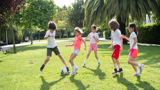 [Translate to Englisch:] Kinder spielen draußen Fußball. 
