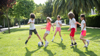 [Translate to Englisch:] Kinder spielen draußen Fußball. 
