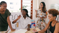 Vier Frauen arbeiten an einem Tisch. 